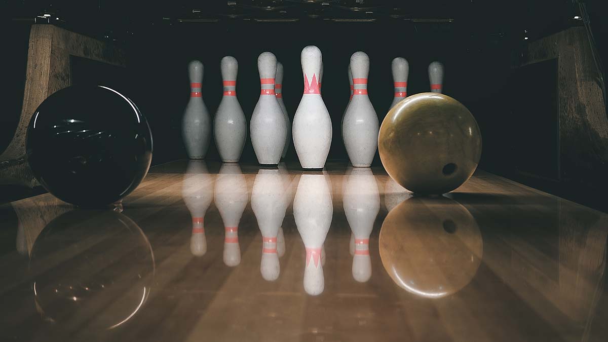 Ten pin bowling lane with balls rolling towards the pins